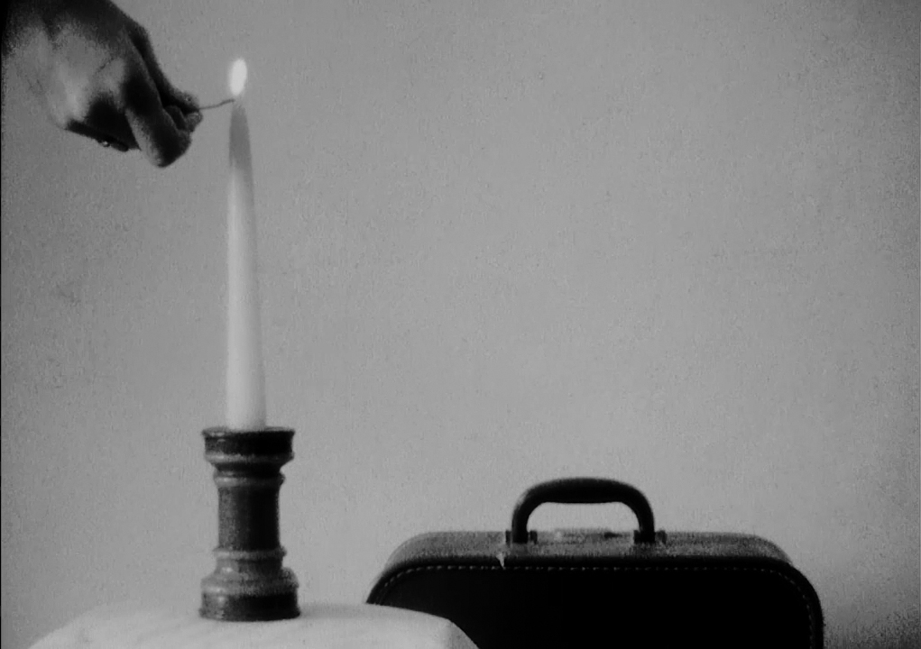 hand lighting a candle next to a suit case