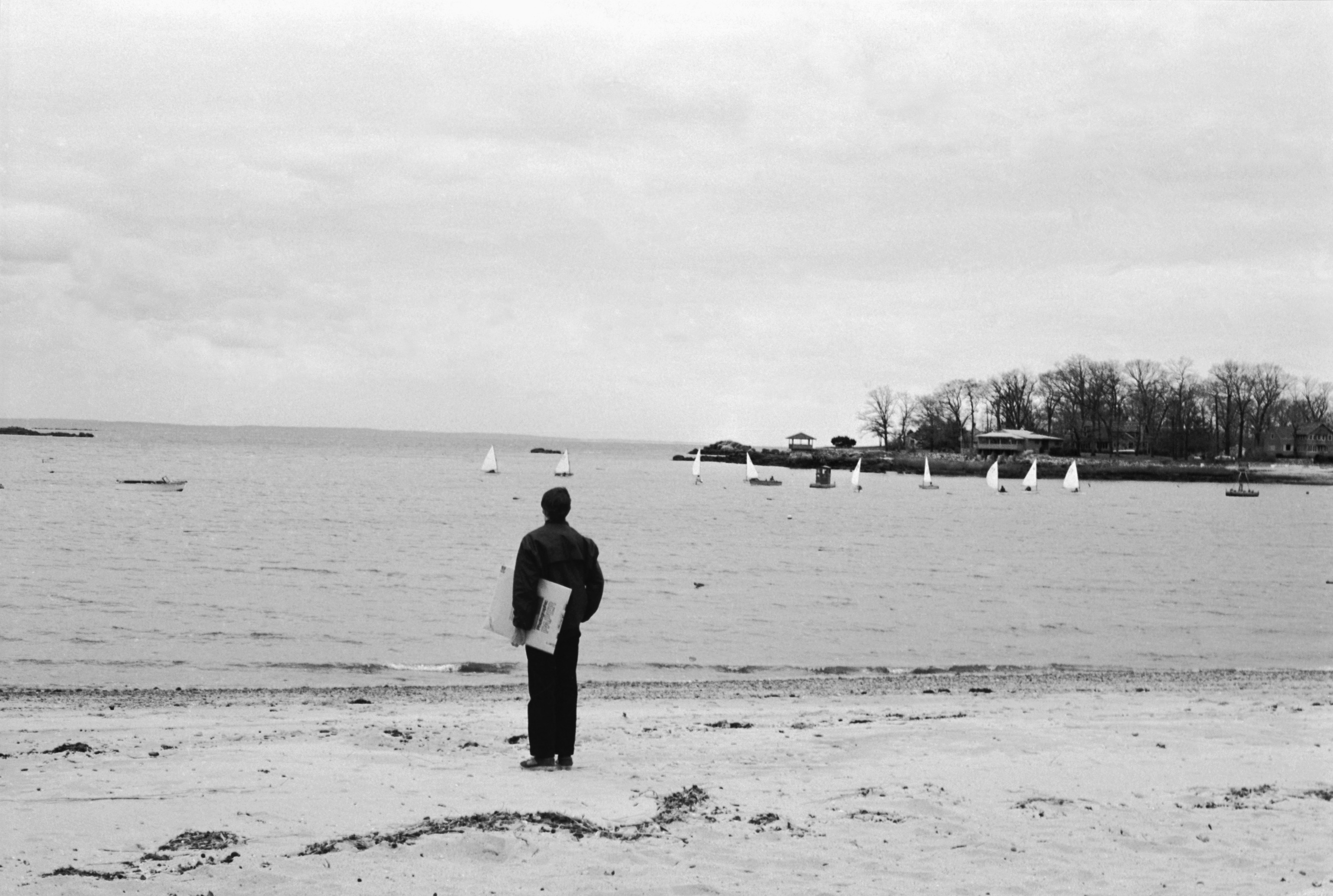 man carrying a box of Kodak paper at the edge of a lake