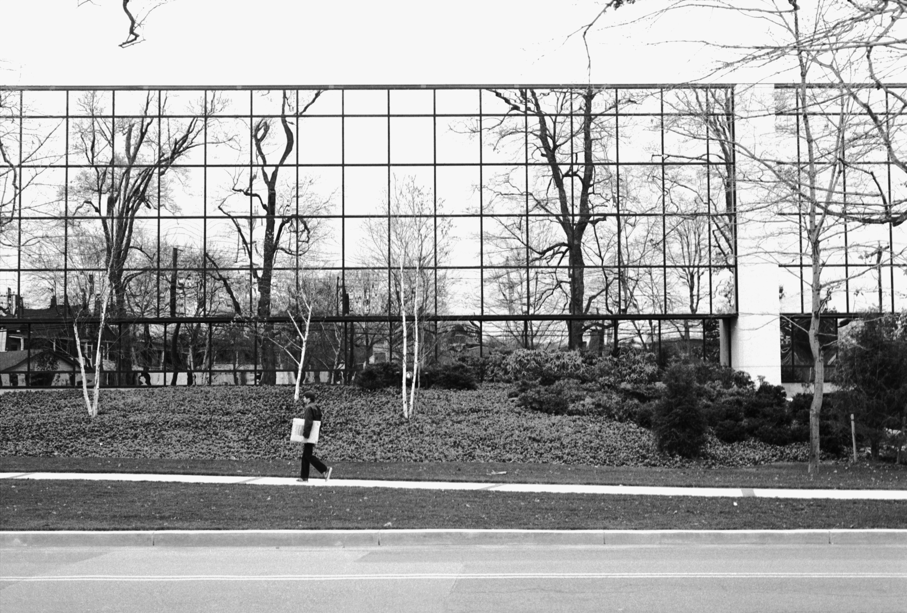man carrying a box of Kodak paper in front of a large building