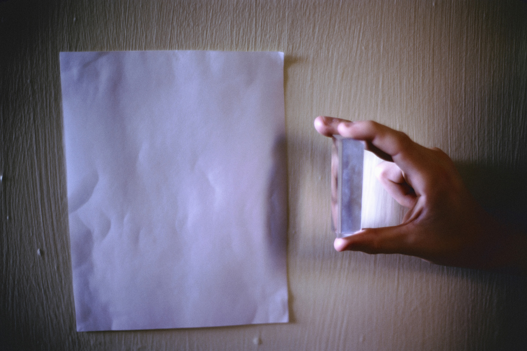 hand holding a prism in front of a sheet of paper